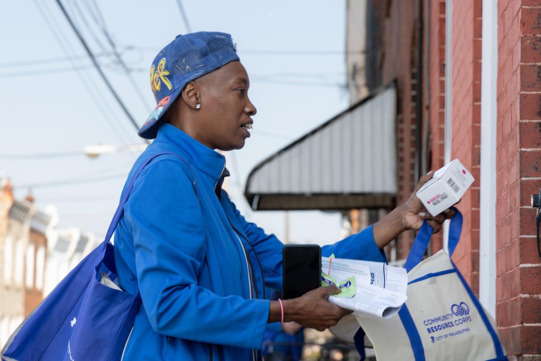 man holding leaflet stands at doorstep