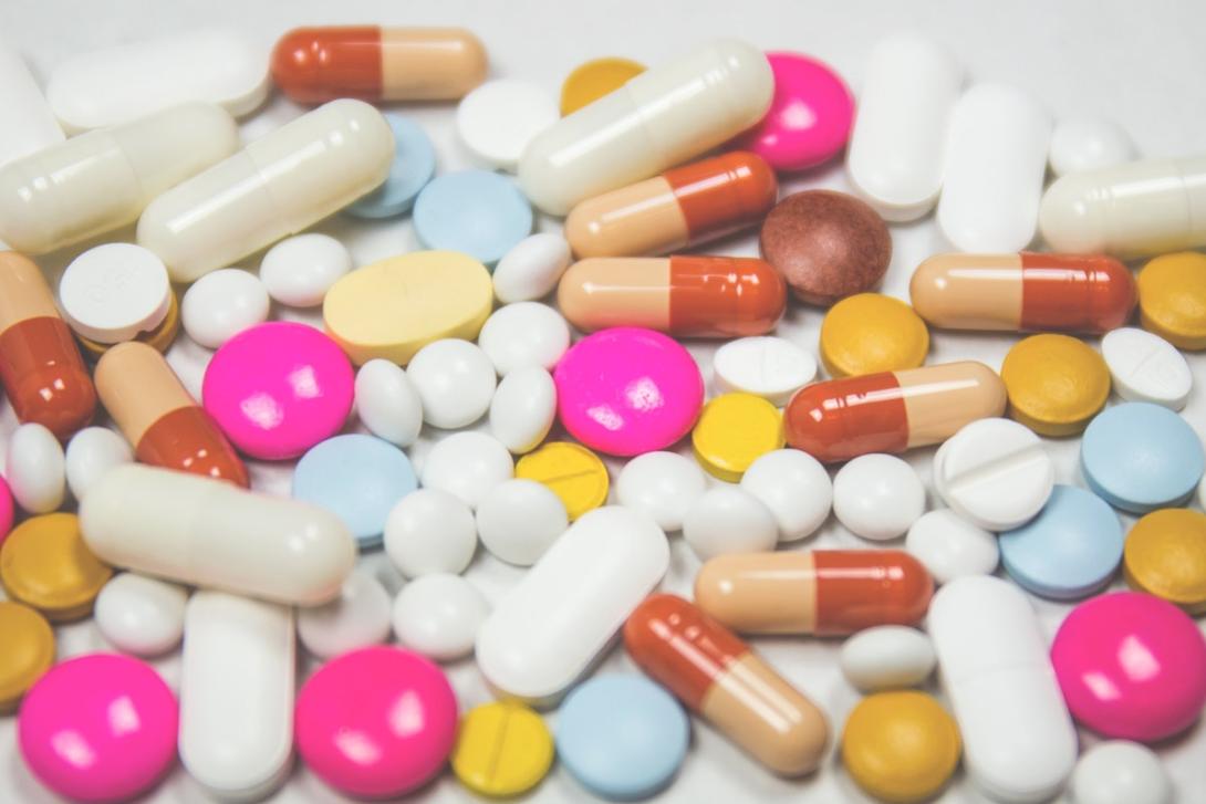 A mix of colorful pills spread out on a counter.